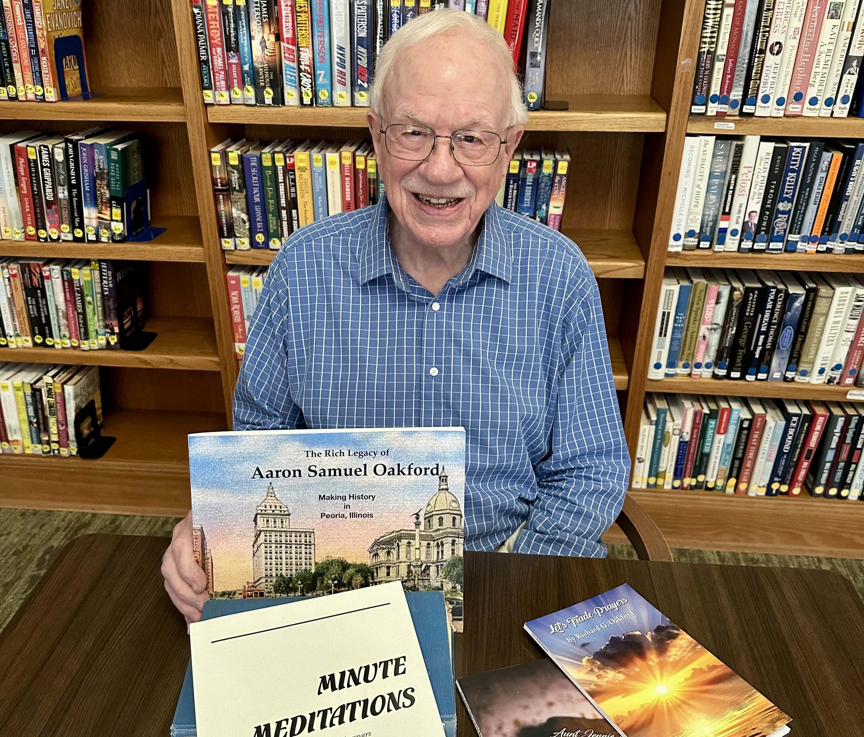 older man with white hair and glasses in a library holding a large history book about aaron samuel oakford